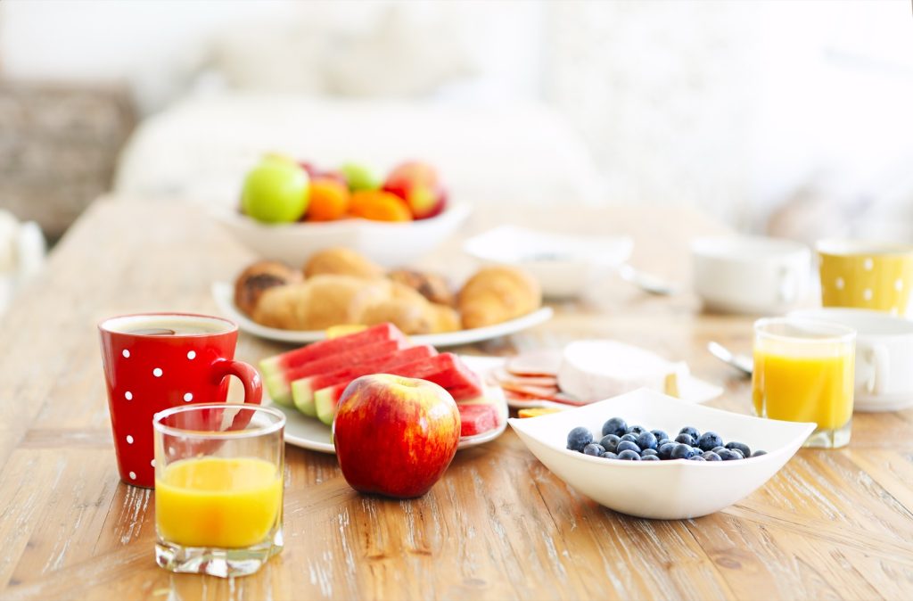 Gezond ontbijt met fruit, blauwe bessen en sinaasappelsap op een houten tafel in ochtendlicht